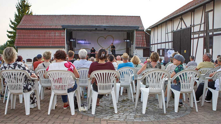 Besucher auf Stühlen mit Bühne im Hintergrund