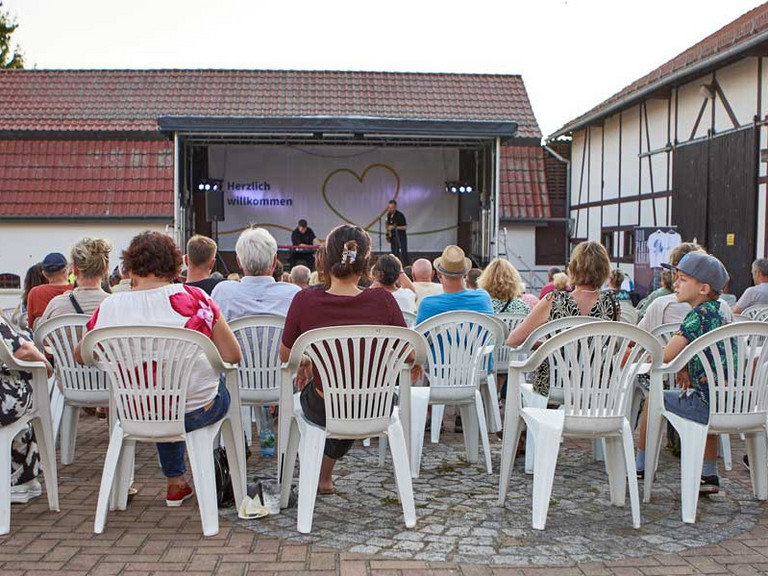 Besucher auf Stühlen mit Bühne im Hintergrund Besucher auf Stühlen mit Bühne im Hintergrund
