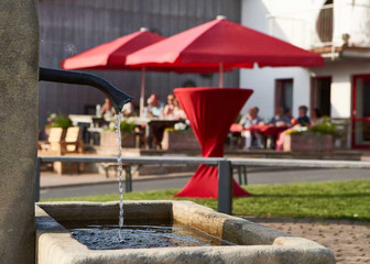 Brunnen und Hof mit Schirmen im Hintergrund