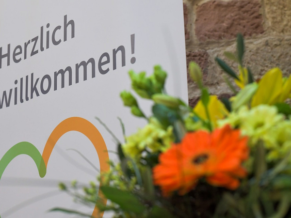 Blumenstrauß vor einem Plakat mit der Aufschrift "Herzlich willkommen" beim Zusammenschluss von Diakonie Werratal und Immanuel Diakonie Südthüringen im Meininger Ortsteil Walldorf