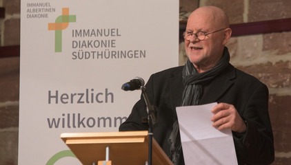 Der frühere Ortspfarrer von Walldorf, Heinrich Freiherr von Berlepsch, spricht am Rednerpult in ein Mikrofon und hält ein Blatt in der Hand beim Zusammenschluss von Diakonie Werratal und Immanuel Diakonie Südthüringen im Kressehof im Meininger Ortsteil Walldorf 